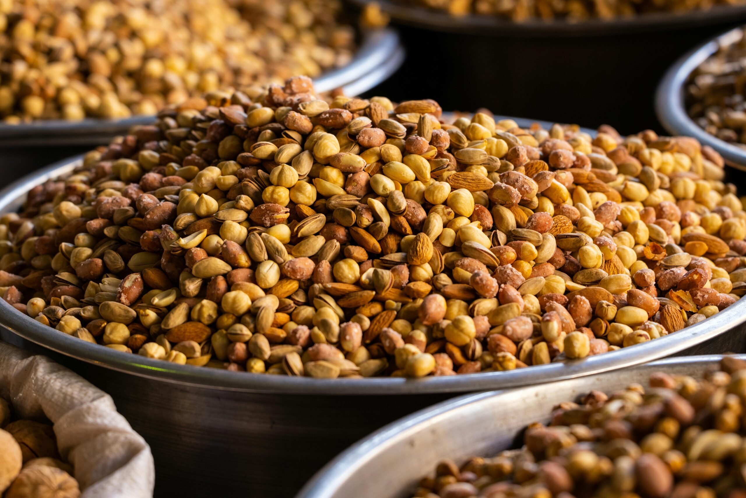 A close-up of assorted roasted nuts in stainless steel bowls, ideal for healthy snacking.