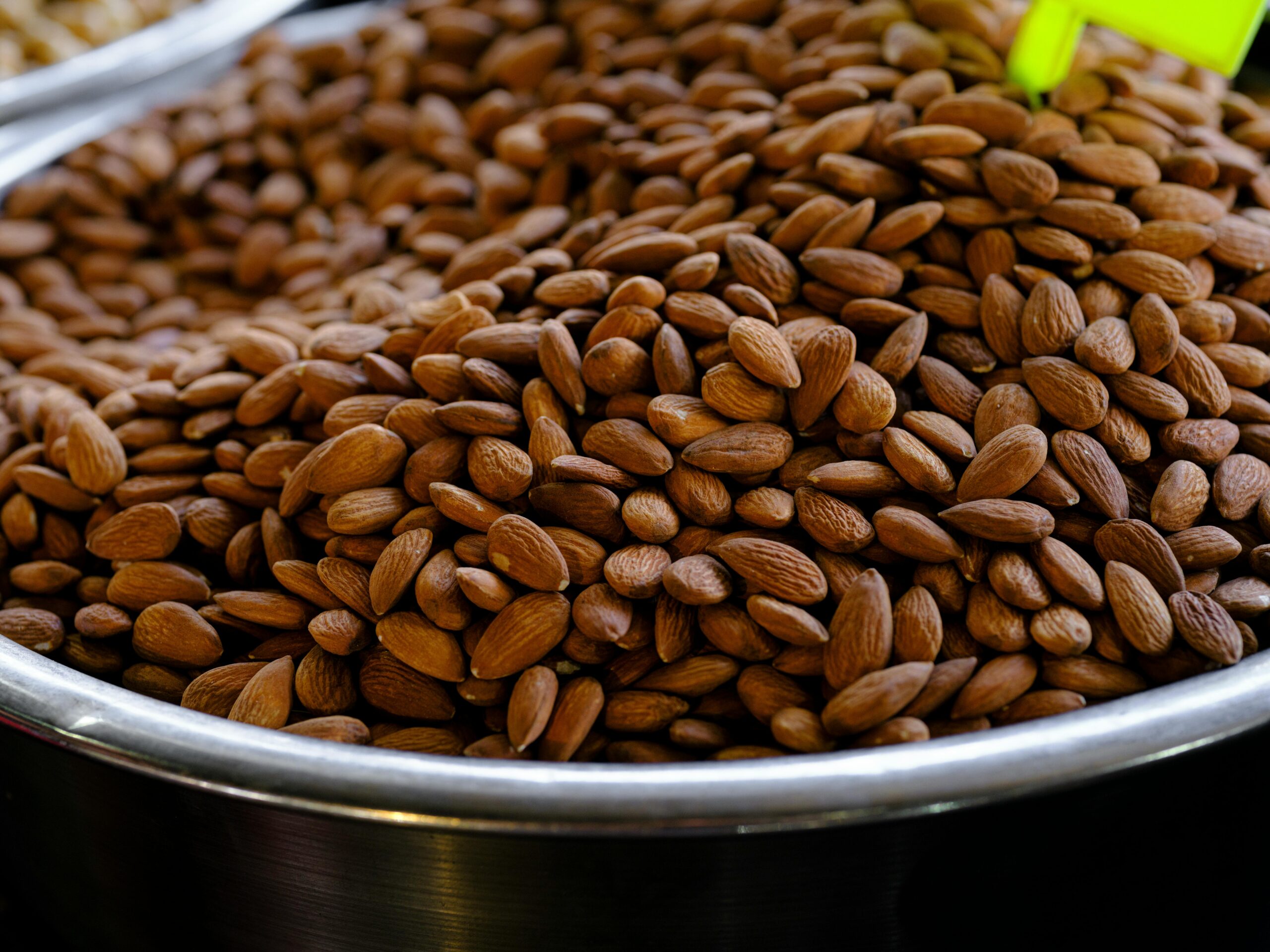 High-quality image of raw almonds displayed in a stainless steel bowl at a market.